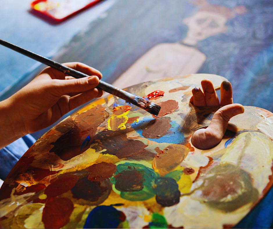 Mani che dipingono con tavolozza di colori